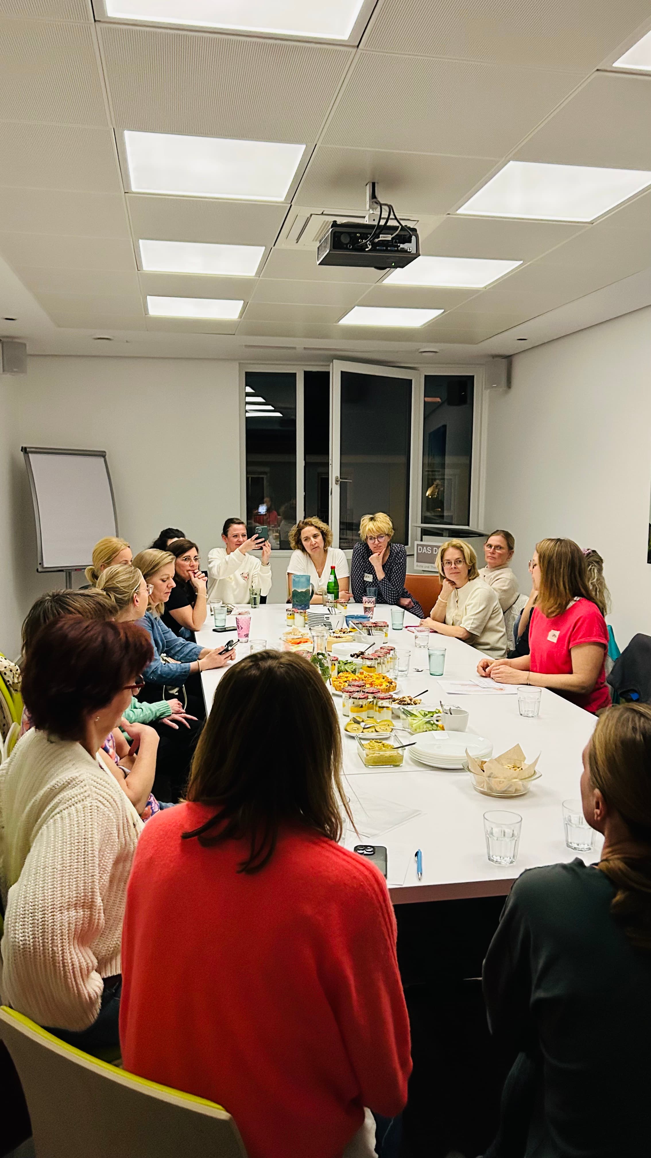Gruppe sitzt gemeinsam am Tisch beim Community Event im DOK:TOR